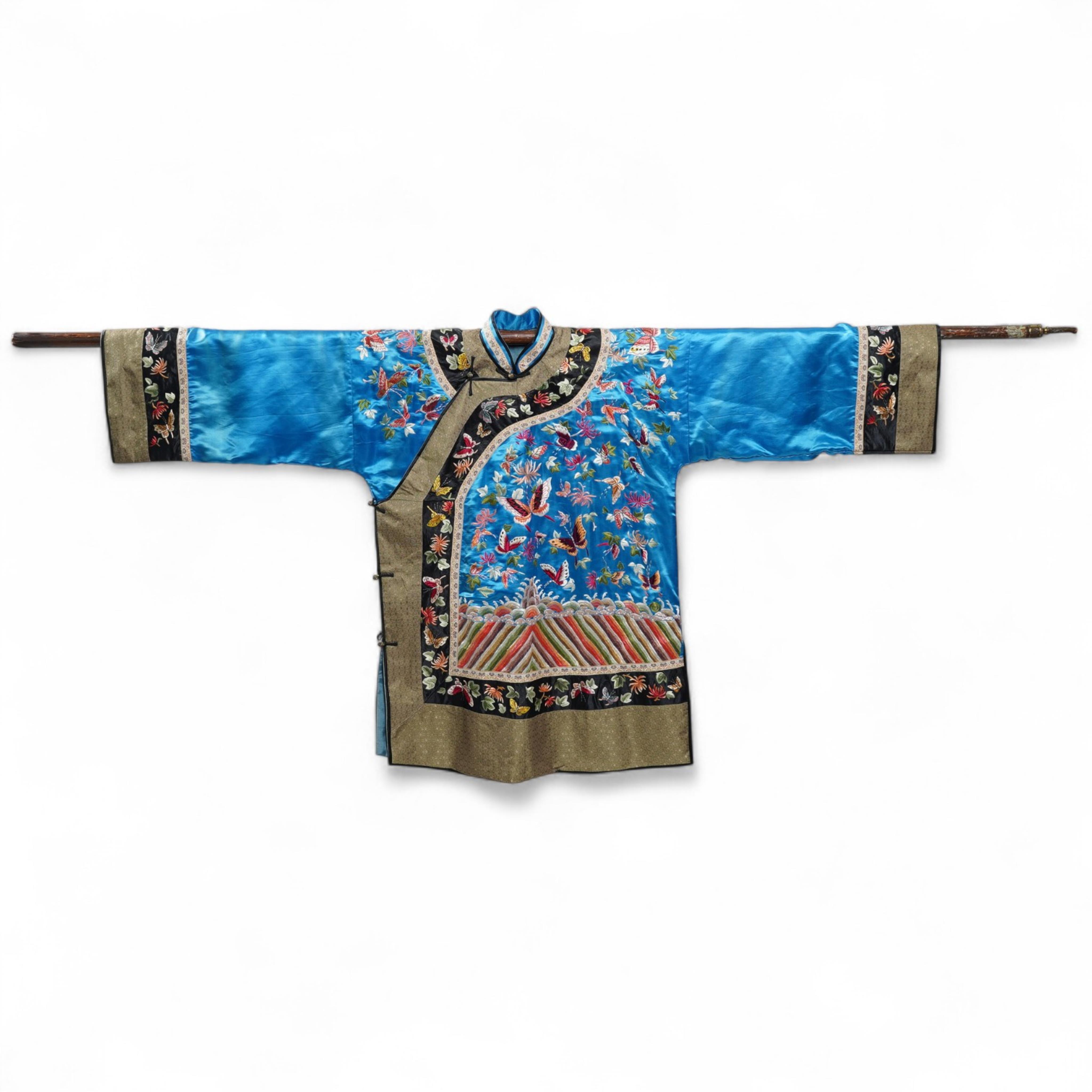 A mid 20th century Chinese turquoise silk jacket, with all over polychrome butterfly embroidery, similar embroidered sleeve bands, front and bottom edges on black silk, all bordered with gold brocade. The jacket blue sil